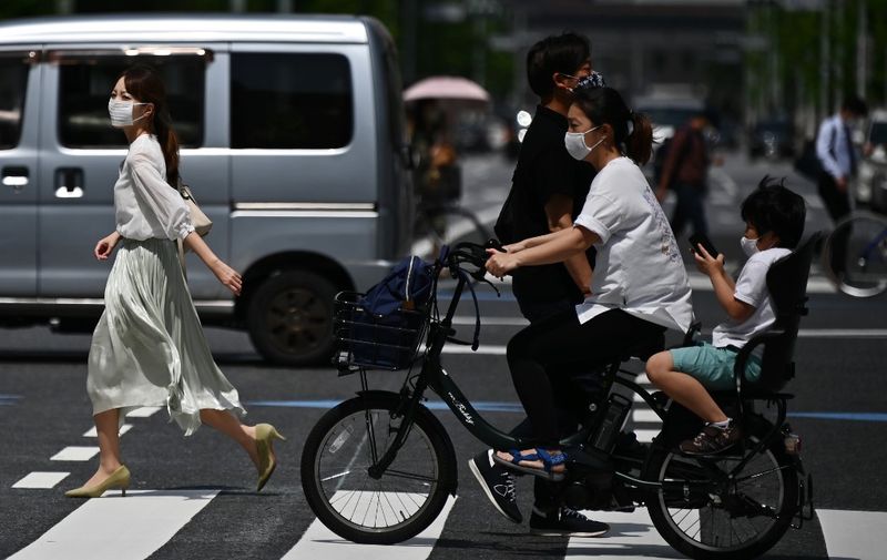 People wearing face masks amid the COVID-19 coronavirus outbreak walk across a street in Tokyo on May 13, 2020. (Photo by Charly TRIBALLEAU / AFP)