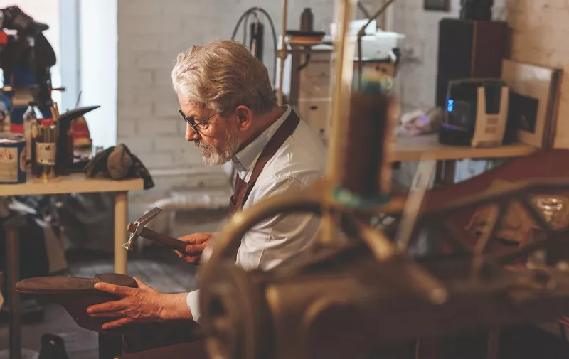 An elderly shoemaker at work in the workshop