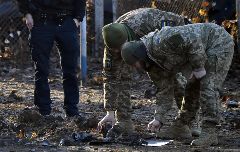 Ukrainian police and military experts collect fragments of downed Russian drone near a crater in a yard amid residential buildings in Kyiv on November 25, 2023, amid the Russian invasion of Ukraine. Ukraine said it had downed 71 Russian attack drones overnight in what Kyiv authorities said was the biggest attack on the capital since the start of the invasion. (Photo by Sergei SUPINSKY / AFP)