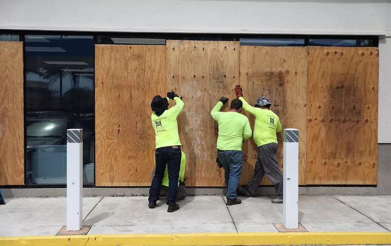 MIAMI BEACH, FLORIDA - AUGUST 30: Workers place plywood over windows as they prepare a business for the possible arrival of Hurricane Dorian on August 30, 2019 in Miami Beach, Florida. Dorian could be a Category 4 storm when it makes landfall as early as Monday somewhere along the Florida coast.   Joe Raedle/Getty Images/AFP