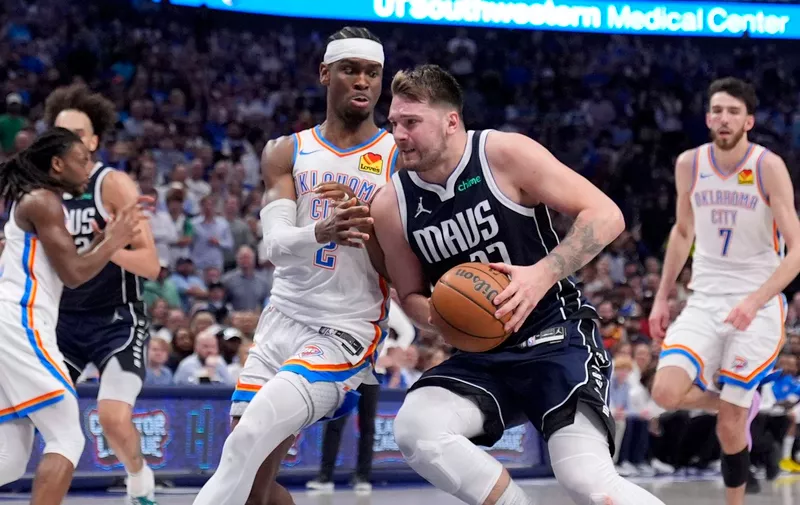 Dallas Mavericks guard Luka Doncic, center right, drives to the basket as Oklahoma City Thunder's Shai Gilgeous-Alexander (2) defends in the second half in Game 4 of an NBA basketball second-round playoff series Monday, May 13, 2024, in Dallas. (AP Photo/Tony Gutierrez)