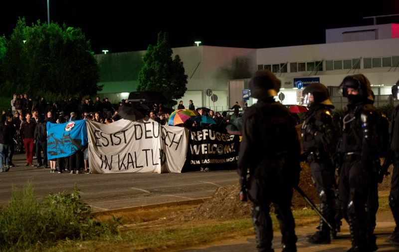 Police faces far-right activists protesting the opening of a new centre for refugees on August 22, 2015 in Heidenau, Germany, a day after similar standoffs left dozens wounded.  Around 1,000 people had turned up in Heidenau, near Dresden, to demonstrate against the expected arrival of hundreds of refugees in a protest called by the far-right National Democratic Party.   AFP PHOTO / DPA / ARNO BURGI +++ GERMANY OUT