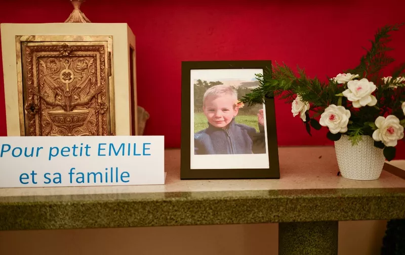 (FILES) This photograph taken on March 21, 2024, inside a chapel in La Bouilladisse southern France, shows a card with the inscription reading "For the little Emile and his family" next to a portrait of Emile, a missing boy, who disappeared on July 8, 2023 in Le Vernet, southeastern France. Two-and-a-half-year-old Emile's bones were found in the Haut-Vernet hamlet, the public prosecutor's office, announced on March 31, 2024. (Photo by CHRISTOPHE SIMON / AFP)