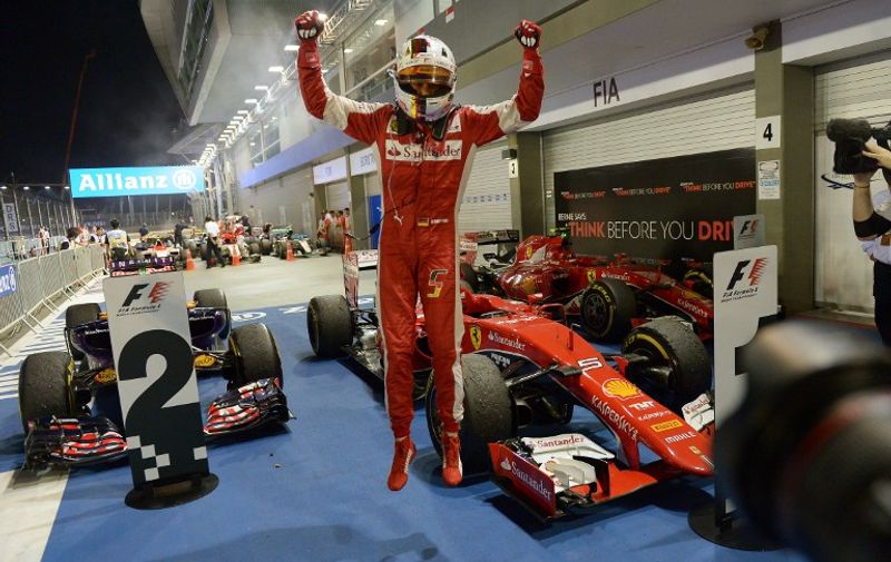 Ferrari's German driver Sebastian Vettel (C) celebrates his victory after winning the Formula One Singapore Grand Prix in Singapore on September 20, 2015.    AFP PHOTO / MOHD RASFAN