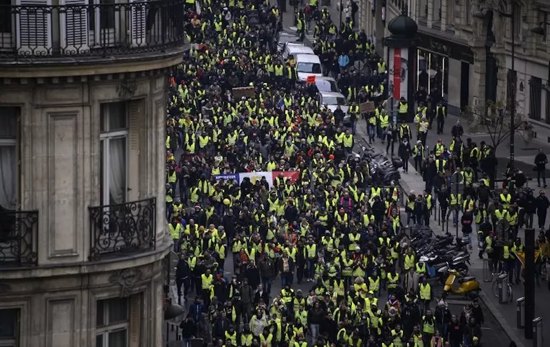 Yellow vest "Gilets Jaunes" march along Rue Quatre September in Paris on January 5, 2019, during a rally by the anti-government protestors. - France's "yellow vest" protestors were back on the streets as a government spokesman denounced those still protesting as hard-liners who wanted only to bring down the government. Several hundred protestors gathered on the Champs Elysees in central Paris, where around 15 police wagons were also deployed, an AFP journalist said. Marches were underway in several other cities across France. (Photo by Olivier MORIN / AFP)