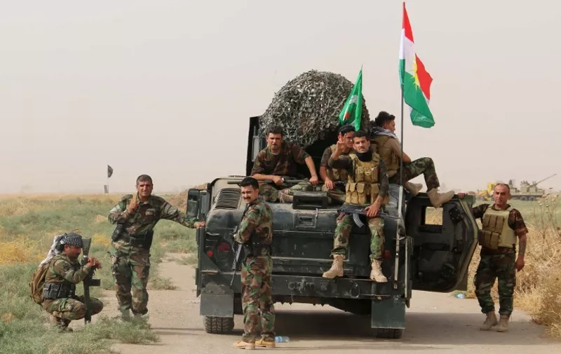 Iraqi Kurdish Peshmerga fighters pose for a photo next to a military vehicle bearing the Kurdish flag after they reportedly captured several villages from Islamic State (IS) group jihadistst in the district of Daquq, south of the northern city of Kirkuk on September 11, 2015. An Iraqi officer said that the operation was launched in the morning with support from international coalition aircraft, and has succeeded in retaking ten villages from IS. AFP PHOTO / MARWAN IBRAHIM