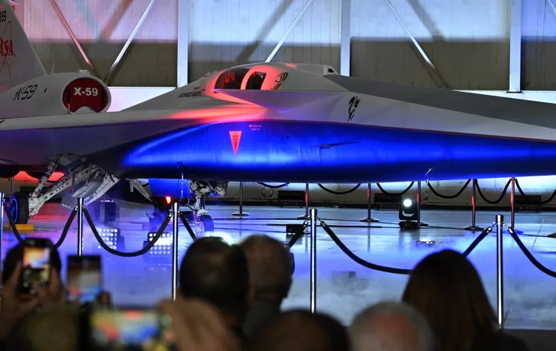 NASA's and Lockheed Martin's X-59 experimental supersonic jet is unveiled during a roll-out ceremony in Palmdale, California, on January 12, 2024. The aircraft, a collaboration with Lockheed Martin Skunk Works, is the centerpiece of NASA's Quesst mission, with the goal of minimizing cross-country travel time by making supersonic flight over land possible.  The US banned supersonic travel over land for non-military aircraft in 1973 due to public concern about sonic booms over populated areas. NASA recently studied transoceanic supersonic flight, which could in theory shuttle passengers from New York City to London in under two hours. (Photo by Robyn Beck / AFP)