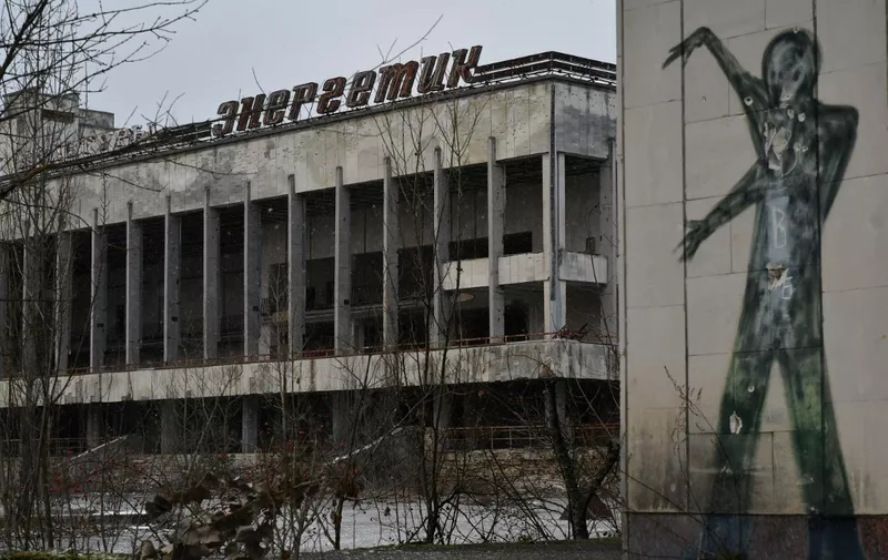 A photograph taken on December 8, 2020 shows a graffiti on a building wall on the central square of the ghost town of Pripyat, not far from Chernobyl nuclear power plant. - More than three decades after the Chernobyl nuclear disaster forced thousands to evacuate, there is an influx of visitors to the area that has spurred officials to seek official status from UNESCO. Officials hope recognition from the UN's culture agency will boost the site as a tourist attraction and in turn bolster efforts to preserve ageing buildings nearby. (Photo by GENYA SAVILOV / AFP)
