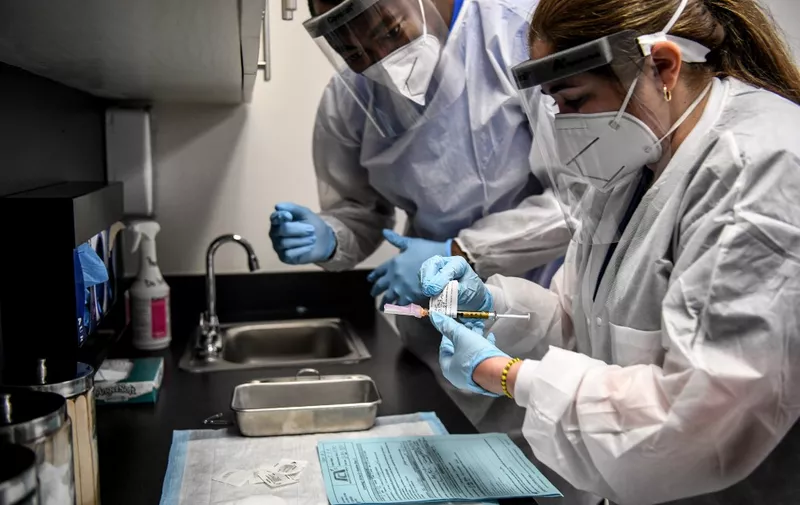 Yaquelin De La Cruz (R) and  Hari Leon Joseph (L) prepare a COVID-19 vaccine for vaccination at the Research Centers of America in Hollywood, Florida, on August 13, 2020. (Photo by CHANDAN KHANNA / AFP)