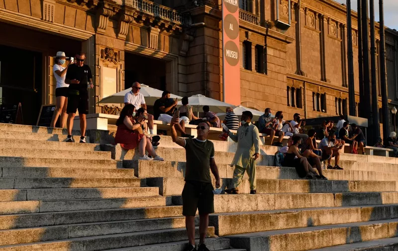People sit on the stairs of the National Art Museum of Barcelona (MNAC) in Barcelona on July 25, 2020. The Catalan government ordered the closure of all nightclubs, discos and event halls across this region of northeastern Spain following a surge in cases of coronavirus. (Photo by Pau BARRENA / AFP)