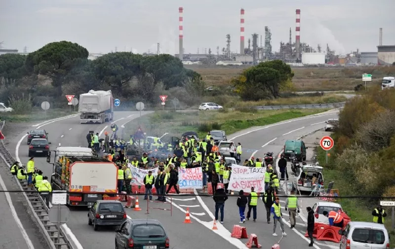 Trucks drive as Yellow Vests (Gilets jaunes) block the road during a demonstration against the rising of the fuel and oil prices on November 19, 2018 near the oil refinery of Fos-sur-mer, southern France. - Around 46,000 people according to police took part across France in a second day of protests on November 18, as some demonstrators vowed to continue their action over the coming days. (Photo by GERARD JULIEN / AFP)