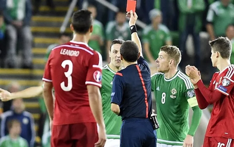 Northern Ireland's defender Chris Baird (2nd L) receives a red card from referee Cuneyt Cakir during the Euro 2016 qualifying group F football match between Northern Ireland and Hungary at Windsor Park in Belfast on September 7, 2015. Kyle Lafferty's priceless late equaliser kept Northern Ireland within touching distance of an historic berth at Euro 2016 as the 10-man hosts rescued a 1-1 draw against Hungary on Monday. AFP PHOTO / MICHAEL COOPER