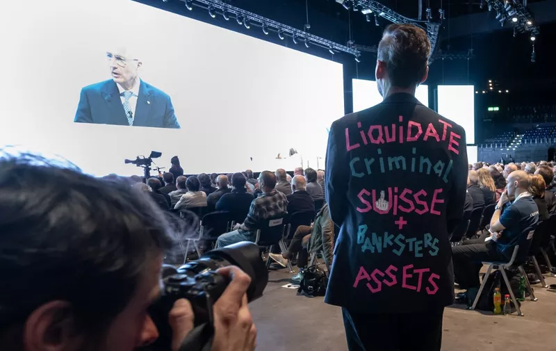 An shareholder wearing a vest reading "Liquidate criminal Suisse and banksters assets" poses for the photographers during the annual general meeting of Credit Suisse bank, in Zurich, on April 4, 2023, following the takeover by UBS of Credit Suisse hastily arranged by the Swiss government on March 19 to prevent a financial meltdown. (Photo by Fabrice COFFRINI / AFP)