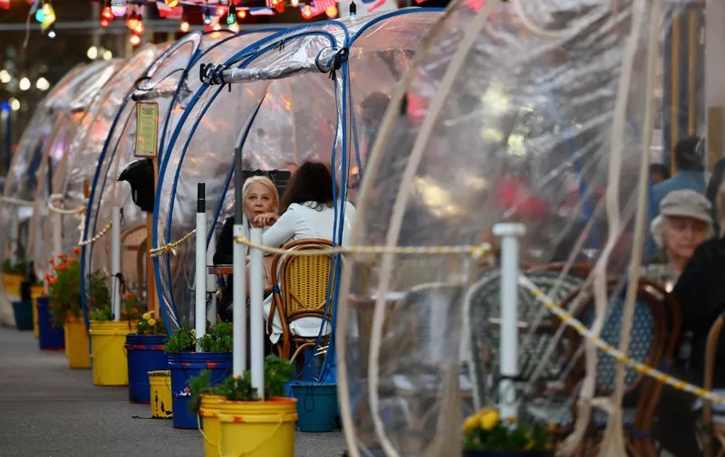 People dine in plastic tents for social distancing at a restaurant in Manhattan on October 15, 2020 in New York City, amid the coronavirus pandemic. (Photo by Angela Weiss / AFP)
