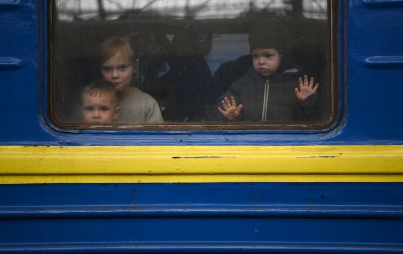 Children look out from a carriage window as a train prepares to depart from a station in Lviv, western Ukraine, enroute to the town of Uzhhorod near the border with Slovakia, on March 3, 2022. - Russian forces have taken over the Ukrainian city of Kherson, local officials confirmed March 2, 2022 the first major urban centre to fall since Moscow invaded a week ago. (Photo by Daniel LEAL / AFP)