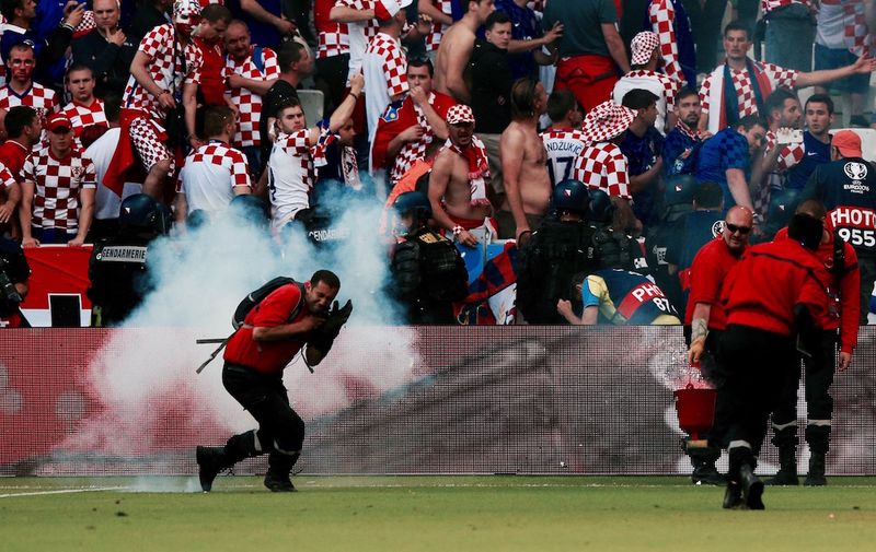 An emergency worker turns away from a thunder flash explosion in front of the Croatia fans, Image: 291406127, License: Rights-managed, Restrictions: Use subject to restrictions. Editorial use only. Book and magazine sales permitted providing not solely devoted to any one team/player/match. No commercial use. Call +44 (0)1158 447447 for further information., Model Release: no, Credit line: Profimedia, Press Association