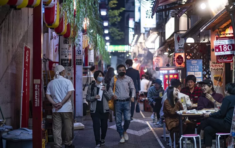 People wearing face masks as a preventive measure against the Covid-19 coronavirus visit the restaurant area of Omoide Yokocho alleyway in Shinjuku district of Tokyo on November 19, 2020. (Photo by Philip FONG / AFP)