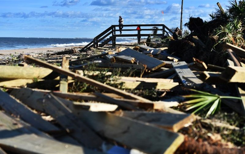 A man leans on a damaged boardwalk in a debris covered beach in St Augustine, Florida, on October 8, 2016, after Hurricane Matthew passed the area.
Hurricane Matthew weakened to a Category 1 storm Saturday as it neared the end of a four-day rampage that left a trail of death and destruction across the Caribbean and up the US Atlantic coast. The full scale of the devastation in hurricane-hit rural Haiti became clear as the death toll surged past 400, three days after Hurricane Matthew leveled huge swaths of the country's south.
 / AFP PHOTO / Jewel SAMAD