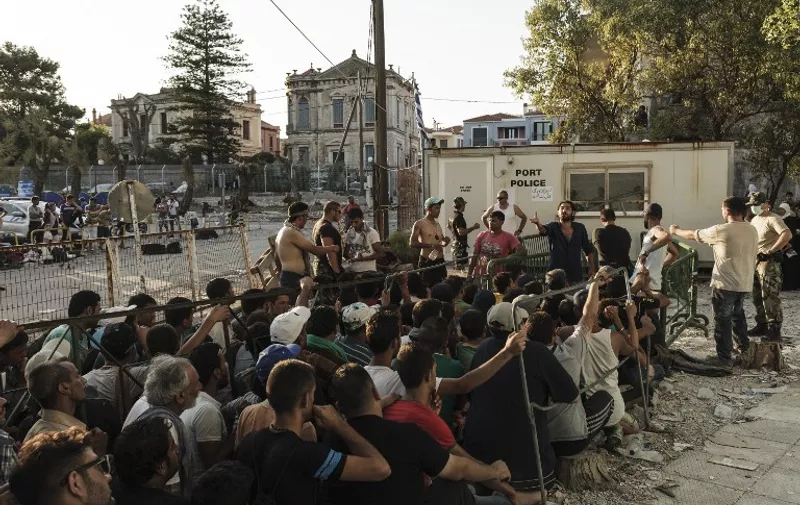 Syrian migrants waiting in line to register with the police authorities at Mytilini port on the island of Lebos, on August 17, 2015. Migrants escaping Syria, Afghanistan, Africa and elsewhere are taking advantage of the calm summer conditions to make daily attempts to cross the Aegean between the Bodrum peninsula and Kos, one of the narrowest waterways between Turkey and the European Union.  AFP PHOTO/ ACHILLEAS ZAVALLIS