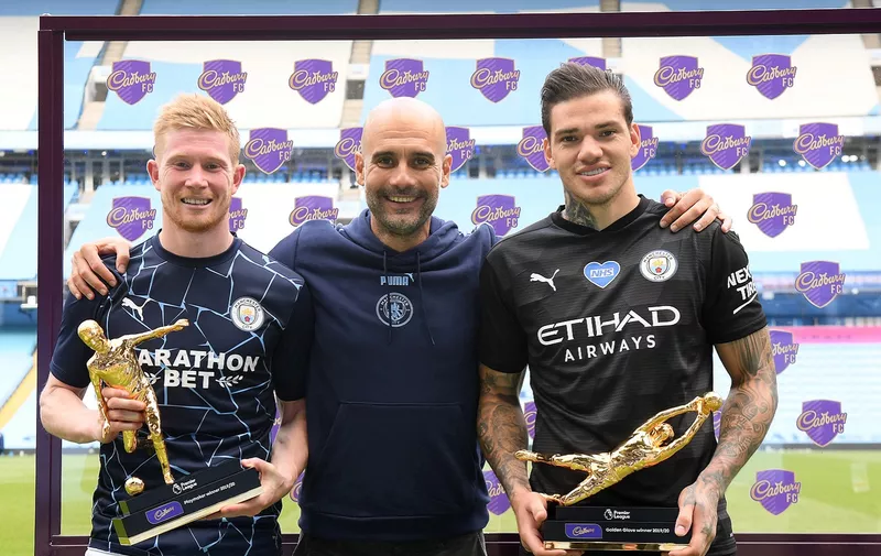 MANCHESTER, ENGLAND - JULY 26:  Ederson of Manchester City  holds the Golden Glove Award and Kevin De Bruyne of Manchester City holds the Playmaker Award alongside Pep Guardiola, Manager of Manchester City after the Premier League match between Manchester City and Norwich City at Etihad Stadium on July 26, 2020 in Manchester, England.Football Stadiums around Europe remain empty due to the Coronavirus Pandemic as Government social distancing laws prohibit fans inside venues resulting in all fixtures being played behind closed doors. (Photo by Shaun Botterill/Getty Images)