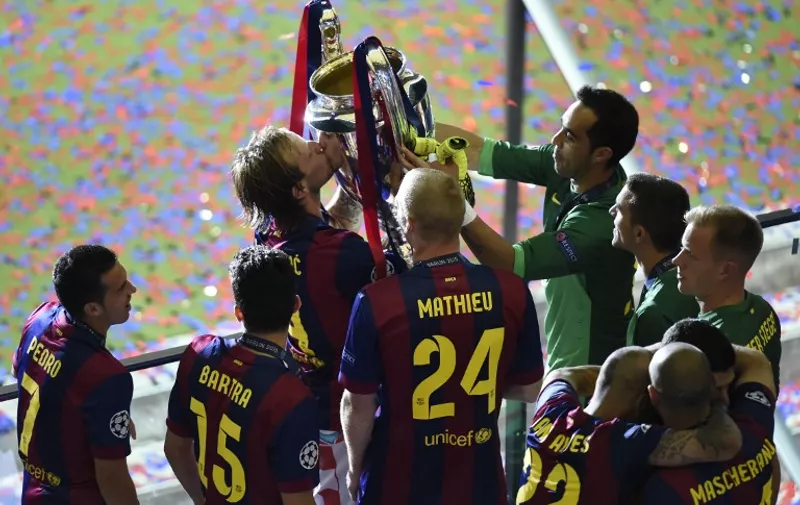 Barcelona's Croatian midfielder Ivan Rakitic kisses the trophy as Barcelona's players celebrate after the UEFA Champions League Final football match between Juventus and FC Barcelona at the Olympic Stadium in Berlin on June 6, 2015.  FC Barcelona won the match 1-3.   AFP PHOTO / ODD ANDERSEN