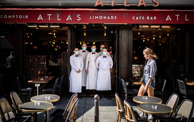 Waiters pose at their terrace of their restaurant rue de Buci in Paris on June 2, 2020, as cafes and restaurants reopen in France, while the country eases lockdown measures taken to curb the spread of the COVID-19 (the novel coronavirus). (Photo by Martin BUREAU / AFP)