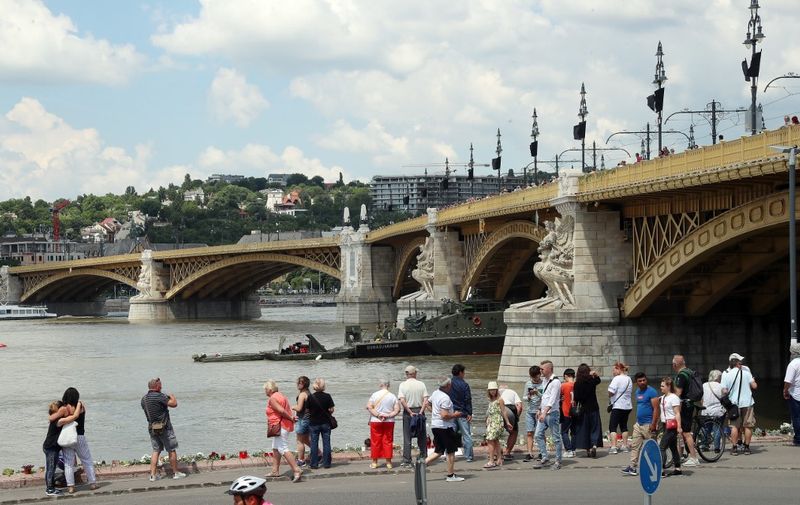 Tourists light candles at the Marit bridge on June 2, 2019 in Budapest, where onlookers gather to watch the operations of experts at the site where a vessel collided with a smaller Mermaid, carrying mainly South Korean tourists, causing it to overturn and sink on a busy stretch of the Danube on June 2, 2019. (Photo by FERENC ISZA / AFP)