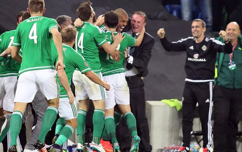 Northern Ireland's midfielder Josh Magennis (C) celebrates with Michael O'Neill with Northern Ireland Manager Micheal O'Neill (3rd R) and teammates after scoring his team's secong goal  during the UEFA Euro 2016 qualifying Group F football match between Northern Ireland and Greece at Windsor Park in Belfast, Northern Ireland, on October 8, 2015.    AFP PHOTO / PAUL FAITH