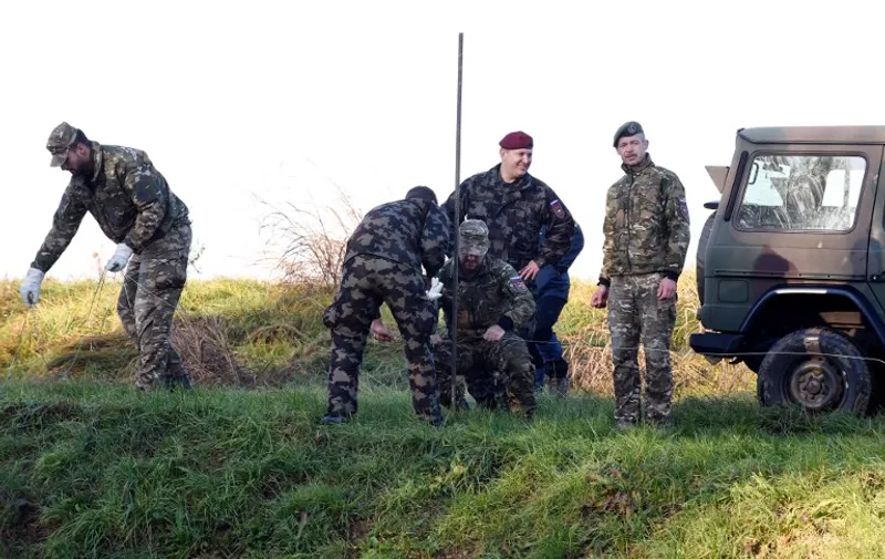 Slovenian soldiers build obstacles on the Slovenian-Croatian border in Sela pri Dobovi near Brezice, on Novemberr 11, 2015. Slovenia on November 10, 2015 outlined plans to build "obstacles", potentially including fences, on its border with fellow EU member Croatia, as it braced for a new spike in migrants bound for northern Europe this week. Prime Minister Miro Cerar, whose country last month found itself on the main Balkans route for thousands of migrants after Hungary sealed its southern borders, insisted however that its frontier would remain open. AFP PHOTO/STRINGER / AFP / STR