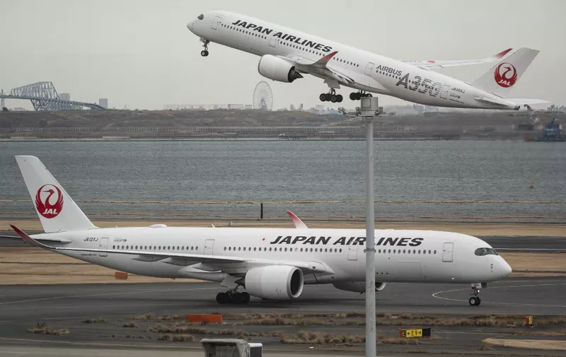 A passenger jet from Japanese carrier Japan Airlines (JAL) takes off past another at Tokyo International Airport at Haneda on February 2, 2023. (Photo by Richard A. Brooks / AFP)