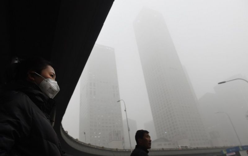 Pedestrians wait to cross a road on a heavily polluted day in Beijing on December 1, 2015. China has ordered thousands of factories to shut as it grapples with swathes of choking smog that were nearly 24 times safe levels on December 1, casting a shadow over the country's participation in Paris climate talks. A thick grey haze shrouded Beijing, with the concentration of PM 2.5, harmful microscopic particles that penetrate deep into the lungs, climbing as high as 598 micrograms per cubic metre. AFP PHOTO / GREG BAKER / AFP / GREG BAKER