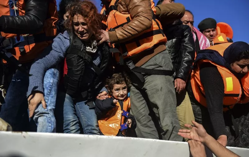 A young girl reacts as migrants and refugees disembark from a boat as they arrive on the Greek island of Lesbos after crossing the Aegean Sea from Turkey on November 26, 2015. More than 800,000 migrants and refugees have crossed the Mediterranean to Europe this year, the UN said on November 13, warning the Greek island of Lesbos especially was overstretched, with thousands, including young children, forced to sleep outside.  / AFP / BULENT KILIC