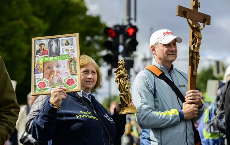 A protester displays a placard reading: "We love life" (L) as another one displays a crucifix during the annual anti-abortion "March for Life" demonstration in Berlin on September 17, 2022. (Photo by John MACDOUGALL / AFP)