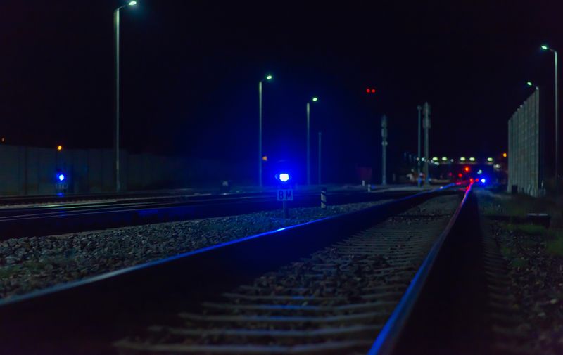 Night empty railroad tracks near train station with lights in dark night.A train station near railway.Photo from railway.Selective focus.,Image: 629512410, License: Royalty-free, Restrictions: , Model Release: yes