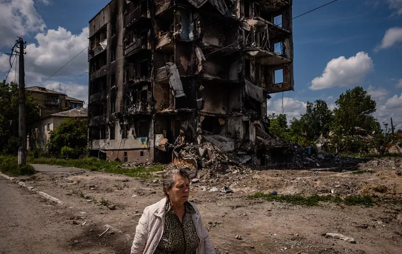 A woman walks past a destroyed apartment building in the town of Borodyanka on June 1, 2022, amid the Russian invasion of Ukraine. (Photo by Dimitar DILKOFF / AFP)