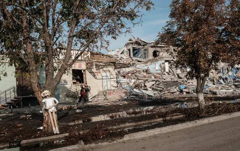 EDITORS NOTE: Graphic content / Local residents walk past destroyed shops and houses on the recently retaken Oskil River's eastern bank in Kupiansk, eastern Ukraine on September 29, 2022. (Photo by Yasuyoshi CHIBA / AFP)