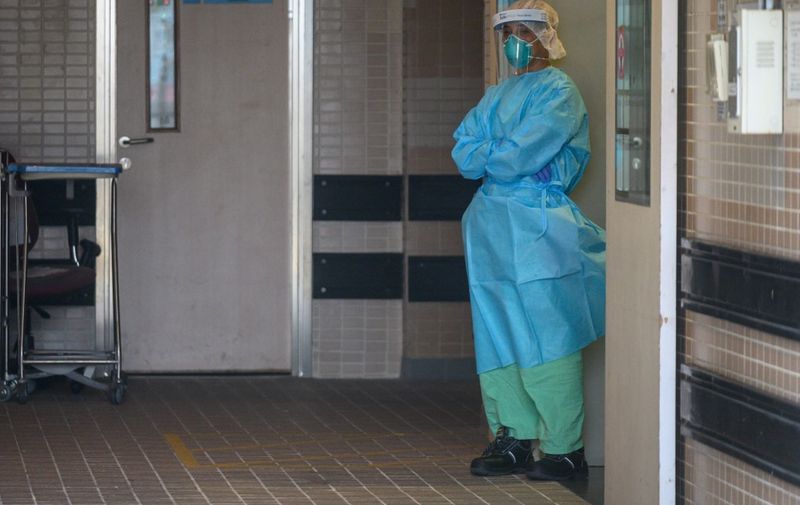 A member of the medical staff, wearing protective clothing to help stop the spread of a deadly SARS-like virus which originated in the central Chinese city of Wuhan, stands at an entrance to Princess Margaret Hospital in Hong Kong on January 26, 2020. - Hong Kong on January 25 classified the virus outbreak as an "emergency" -- the city's highest warning tier -- and announced ramped-up measures to reduce the risk of further infections. (Photo by Philip FONG / AFP)