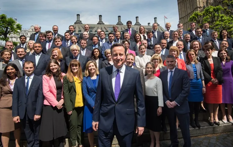 British Prime Minister David Cameron (C) poses for a group photo with newly-elected Conservative MPs at the Houses of Parliament in central London on May 11, 2015. British Prime Minister David Cameron unveiled his new cabinet on May 11 after an unexpected election victory that gave his Conservative party a narrow majority in parliament for the first time in nearly 20 years.  AFP PHOTO / POOL / STEFAN ROUSSEAU