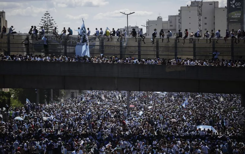 Fans of Argentina wait for the bus with Argentina's players to pass through an avenue to celebrate after winning the Qatar 2022 World Cup tournament in Buenos Aires on December 20, 2022. - Millions of ecstatic fans are expected to cheer on their heroes as Argentina's World Cup winners led by captain Lionel Messi began their open-top bus parade of the capital Buenos Aires on Tuesday following their sensational victory over France. (Photo by Emiliano Lasalvia / AFP)