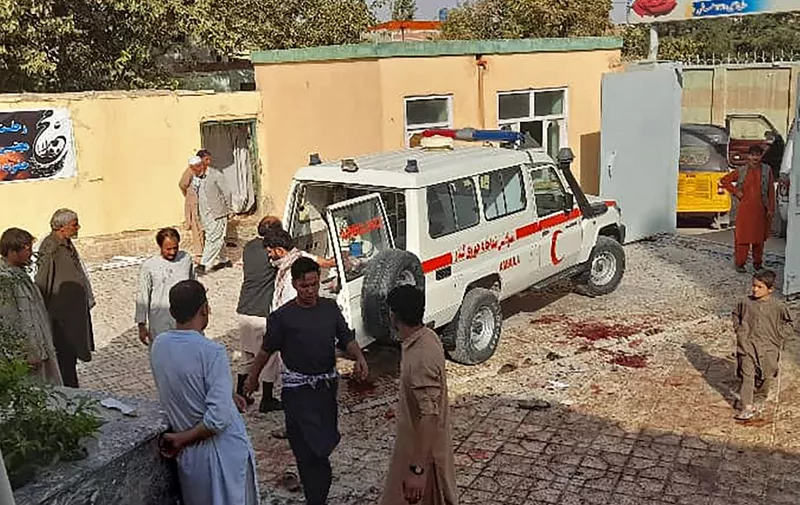 EDITORS NOTE: Graphic content / Afghan men stand next to an ambulance after a bomb attack at a mosque in Kunduz on October 8, 2021. (Photo by - / AFP)