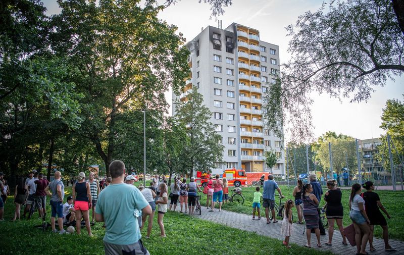 People look on as firefighters work at the scene where a fire broke out in an apartment block in Bohumin, eastern Czech Republic on August 8, 2020, killing eleven people including three children. - Police originally reported ten dead in the fire in a 13-storey concrete block of flats in the city of Bohumin on the Czech-Polish border some 300 kilometres (190 miles) east of the capital Prague. (Photo by Lukas Kabon / AFP)