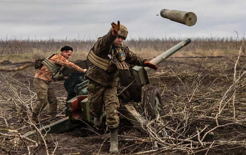 A Ukrainian serviceman of an artillery unit throws an empty shell as they fire towards Russian positions on the outskirts of Bakhmut, eastern Ukraine on December 30, 2022. (Photo by Sameer Al-DOUMY / AFP)