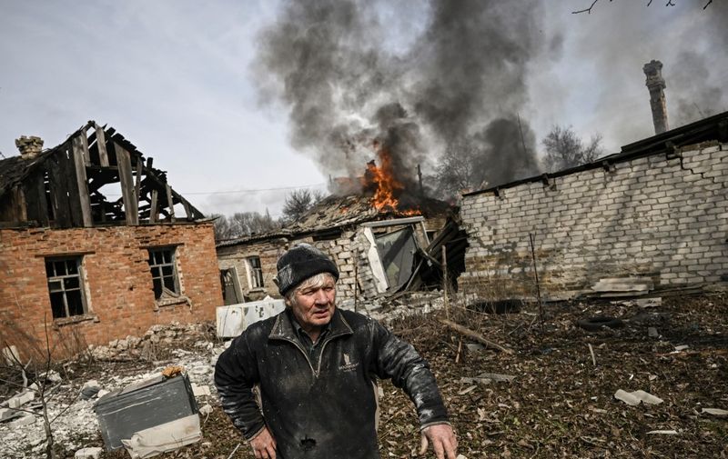 A man stands outside a burning house after shelling in the town of Chasiv Yar, near Bakhmut, on March 21, 2023, amid the Russian invasion of Ukraine. (Photo by Aris Messinis / AFP)