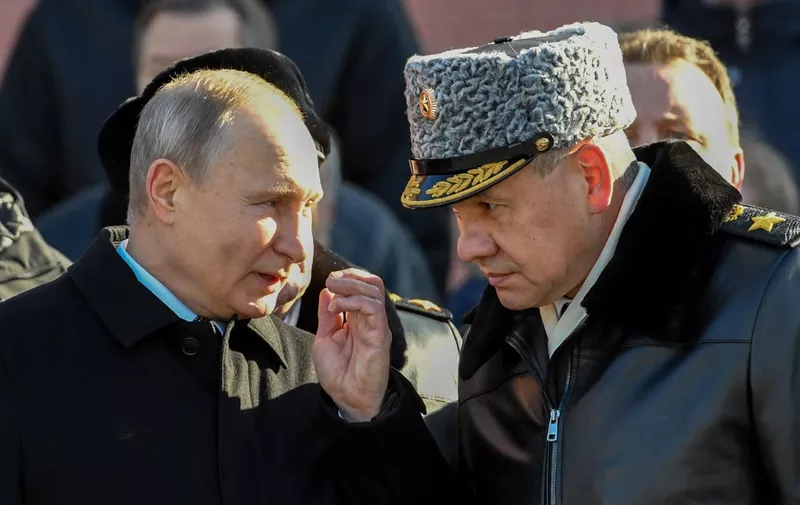 Russian President Vladimir Putin (L) speaks to Defence Minister Sergey Shoygu during a wreath laying ceremony at the Tomb of the Unknown Soldier near the Kremlin wall to mark Defender of the Fatherland Day in Moscow on February 23, 2018. Defender of the Fatherland Day, celebrated in Russia on February 23, honours the nation's army and is a nationwide holiday. (Photo by Yuri KADOBNOV / AFP)
