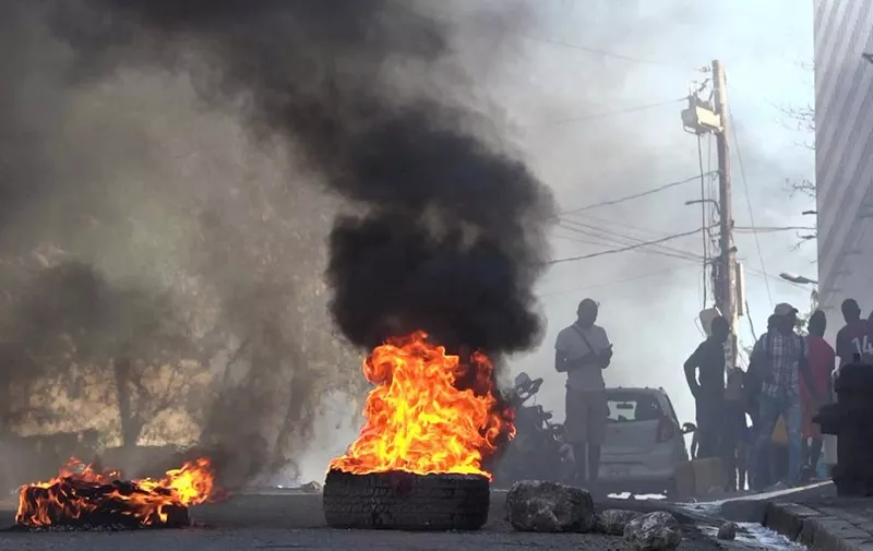 This screen grab taken from AFPTV shows tires on fire near the main prison of Port-au-Prince, Haiti, on March 3, 2024, after a breakout by several thousand inmates. At least a dozen people died as gang members attacked the main prison in Haiti's capital, triggering a breakout by several thousand inmates, an AFP reporter and an NGO said on March 3. "We counted many prisoners' bodies," said Pierre Esperance of the National Network for Defense of Human Rights, adding that only around 100 of the National Penitentiary's estimated 3,800 inmates were still inside the facility after the gang assault overnight on March 2. (Photo by Luckenson JEAN / AFPTV / AFP)