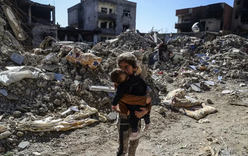 Children walk among the rubble of damaged buildings following heavy fighting between government troops and Kurdish fighters in the Kurdish town of Cizre in southeastern Turkey, which lies near the border with Syria and Iraq, on March 2, 2016. 
Thousands in Turkey's Kurdish-majority town of Cizre started returning to their homes on March 2 after authorities partially lifted a curfew in place since December for a controversial military operation to root out separatist rebels.  / AFP / ILYAS AKENGIN
