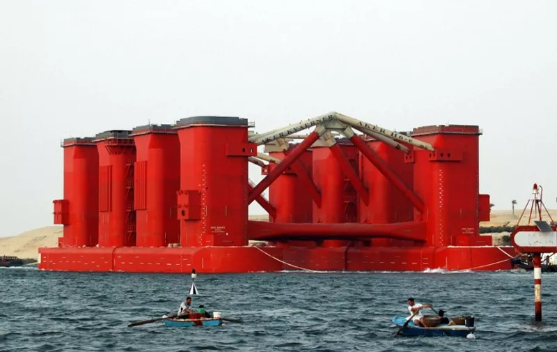Egyptian fishermen sail close to Aker Solutions' H-6e, the world's largest drilling rig, transits in the Suez canal near to Ismailia city on May 8, 2008, on its way to Norway from being built in Dubai. The H-6e drilling rig is the most advanced semi-submersible platform used to drill for oil at depths of up to 3000 metres with a maxium drill length of 10,000 metres. AFP PHOTO/STR