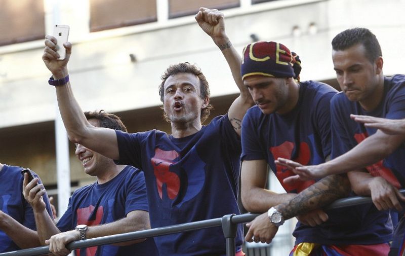 Barcelona's coach Luis Enrique (L) gestures on a bus parading through the streets of Barcelona as the team celebrate its victory over Juventus one day after the UEFA Champions League final football on June 7, 2015. Luis Suarez and Neymar scored second-half goals to give Barcelona a 3-1 Champions League final victory over Juventus on June 6, 2015 as the Spaniards became the first team to twice win the European treble.   AFP PHOTO/ QUIQUE GARCIA