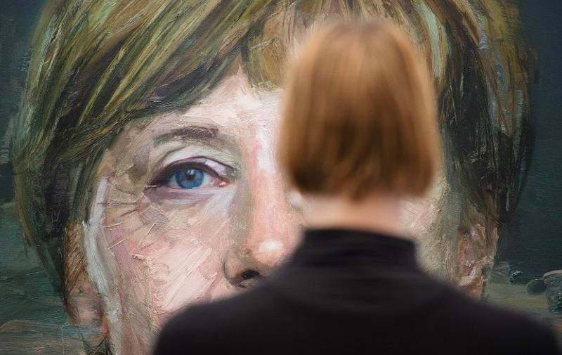 A woman poses for a photograph with artwork entitled "Portrait of Angela Merkel" by Colin Davidson, during a press preview at the London Art Fair in north London on January 19, 2016. The fair is set to run until January 24.  AFP PHOTO / LEON NEAL

RESTRICTED TO EDITORIAL USE, MANDATORY MENTION OF THE ARTIST UPON PUBLICATION, TO ILLUSTRATE THE EVENT AS SPECIFIED IN THE CAPTION / AFP / LEON NEAL