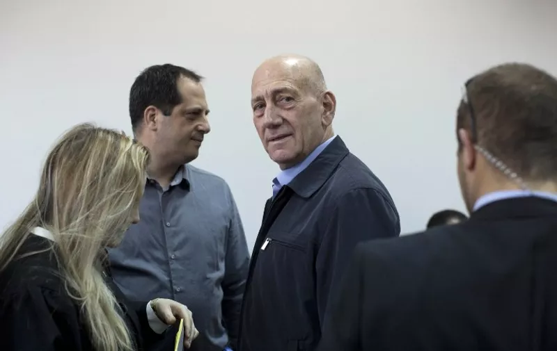 Former Israeli prime minister Ehud Olmert (C) stands at the court room in Jerusalem's District Court, on March 30, 2015.  A Jerusalem court found Olmert guilty of corruption over allegations that he received envelopes of cash from a US businessman, Israeli media reported.  AFP PHOTO / POOL / ABIR SULTAN